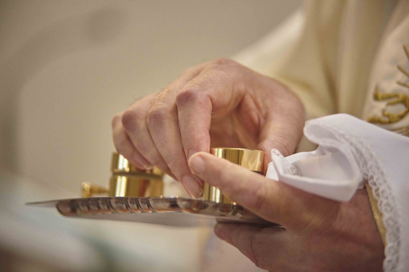 Priest's hands holding the containers of chromium scars and catechumens for the rite of baptism.